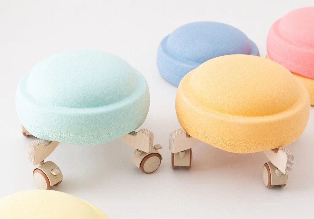 Pastellfarbene Stapelsteine auf Holz Rollern als Zubehör für Bewegungsparcours im Kinderzimmer