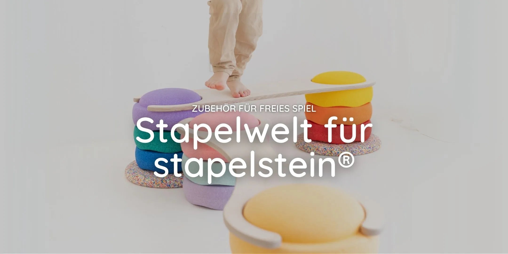 Banner Stapelwelt für stapelstein: Kind balanciert auf Holzbrücke über bunten Stapelsteinen, Text Zubehör für freies Spiel